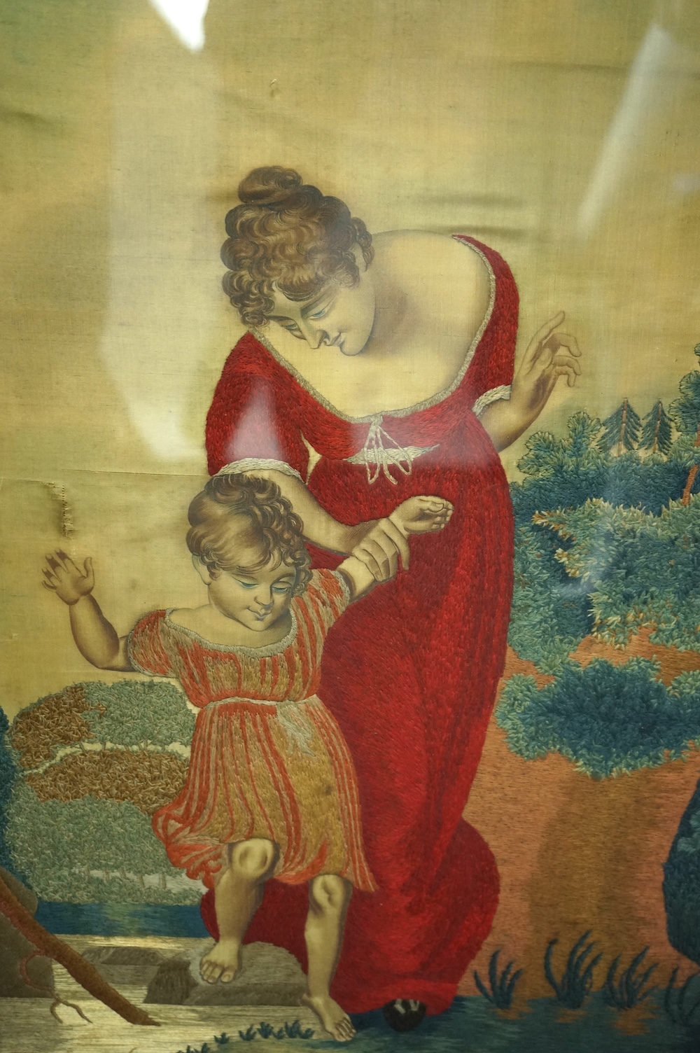 Two Regency silk embroidered and painted figurative panels. Both mother and child scences. One an intimate farmyard scene, embroidered with mother and child, flowers, a cat and pigs. The other of a mother helping her chi